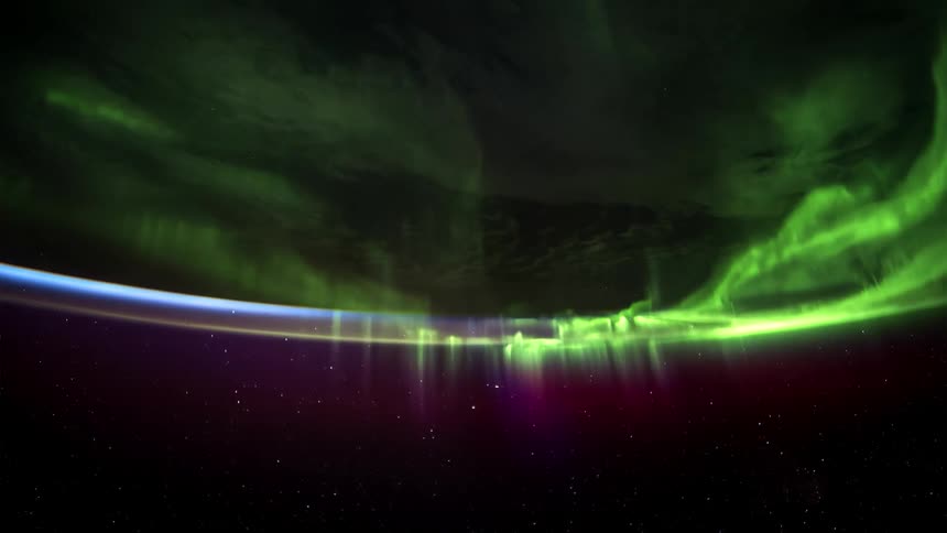 A vibrant display of the northern lights with green and purple hues against a night sky seen from space