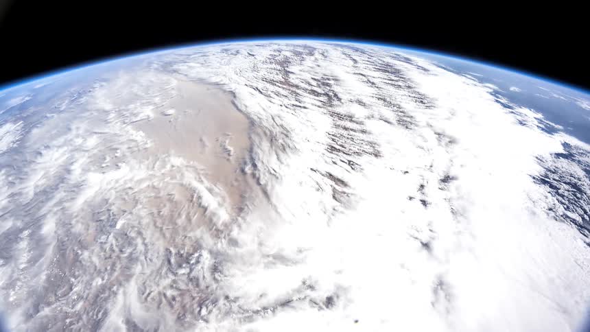 White atmosphere and brown terrain contrast with the blue of the oceans as earth passes below during an orbit