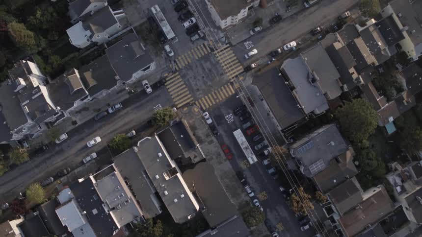 An aerial view of a town showing buildings, and a few cars and trucks going down the streets