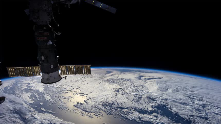 Space station orbits the night side of the earth as the sun sets