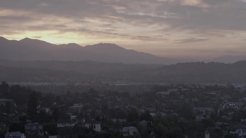 Aerial view of a city with the sun going down behind the mountains in the distance