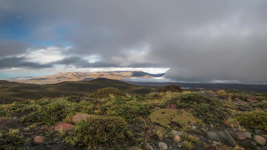 Time lapse of clouds rolling over a vast mountainous landscape with sparse vegetation