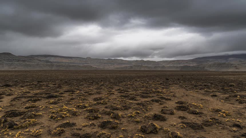 Clouds are moving quickly in the sky above the desert sand