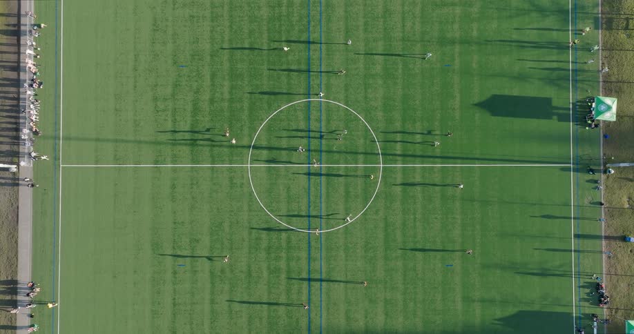 Birds eye view directly over mid field as players move a soccer ball through frame