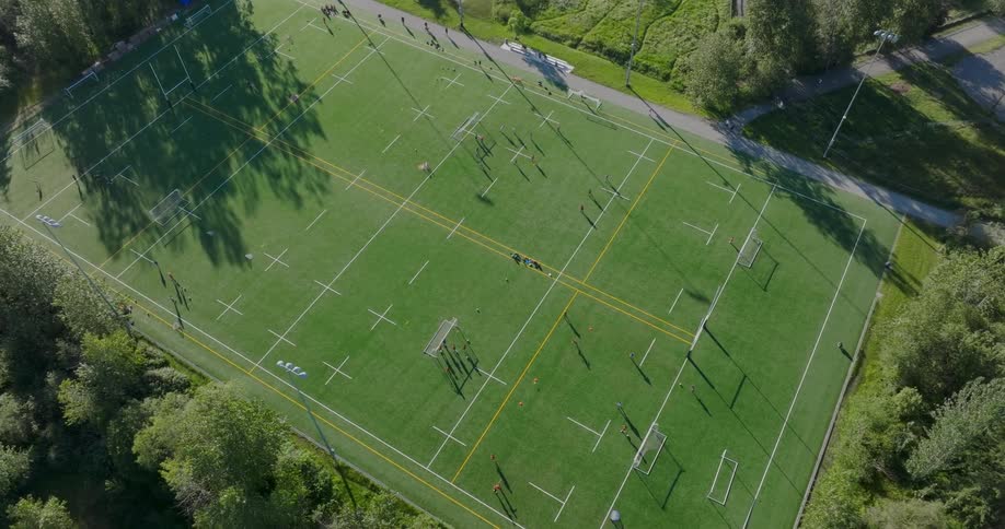 Groups of kids run soccer drills on a field in a city park
