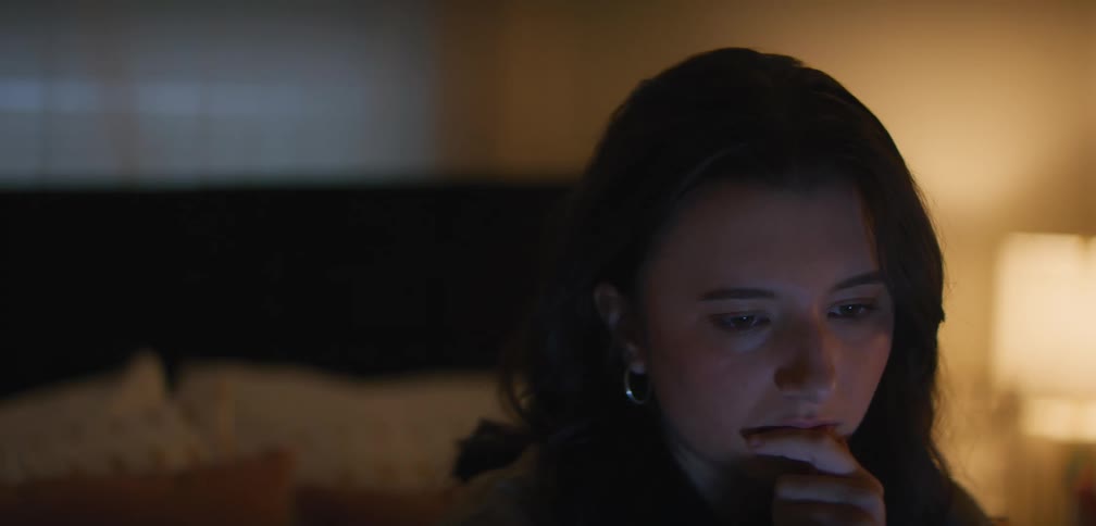 A girl is sitting on her bed with her computer and focusing on homework