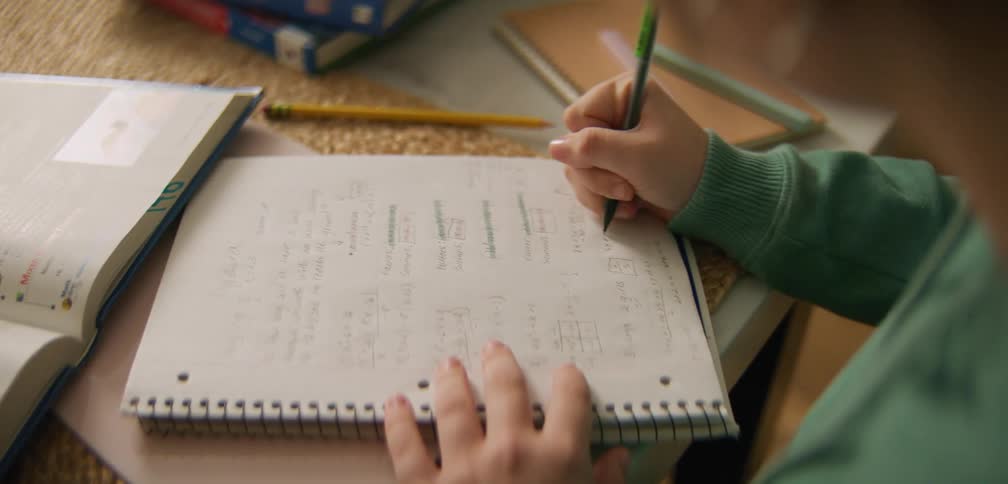 Young student sits at table and works on their math homework