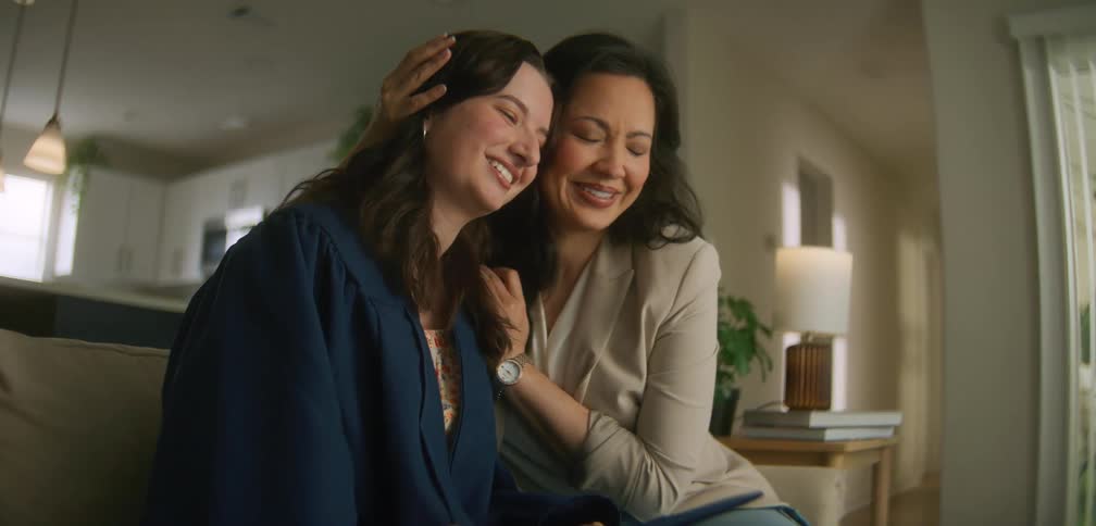 Two women sitting together on a sofa hugging each other affectionately