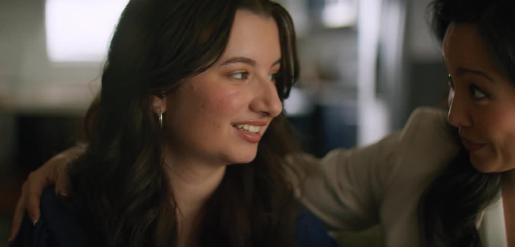 Close up of a woman sitting on a couch at home receiving a hug