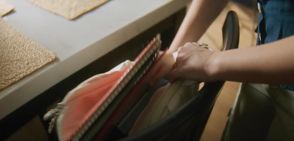 A student filling a backpack with schoolbooks