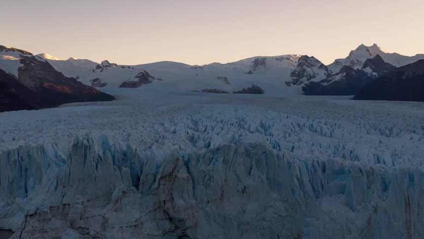 Glaciers surrounded by mountains and the sunset sky in reddish tones