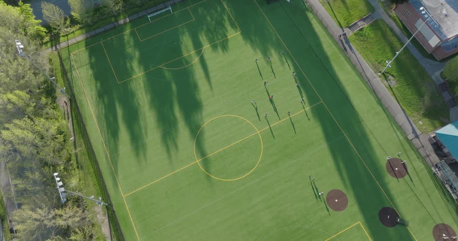 A youth baseball team holds practice drills on a dual purpose turf field prior to a game