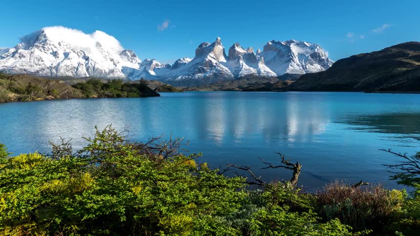 Landscape of a lake that reflects the surrounding nature with mountains on the horizon