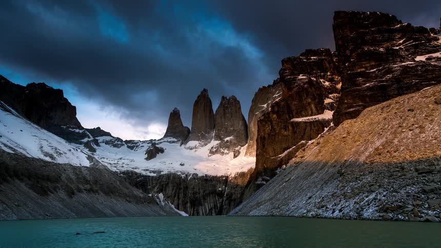 Scenery of a lake surrounded by snowy mountains against a cloudy sky