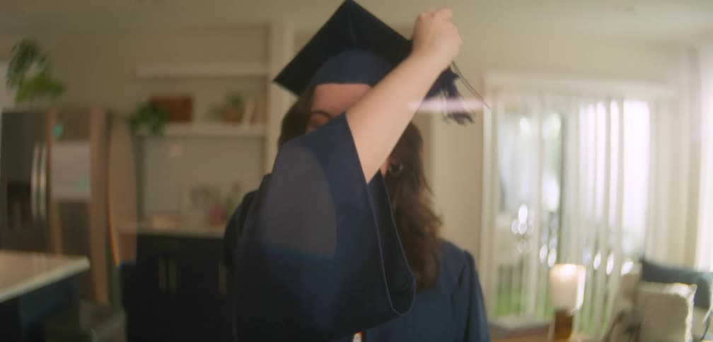 A girl is smiling and wearing graduation attire