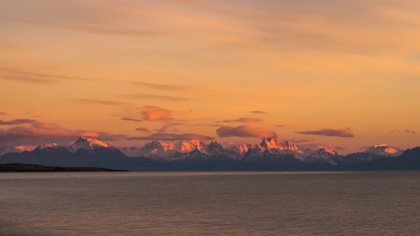 Time lapse of an ocean near a mountain range as the sun is setting