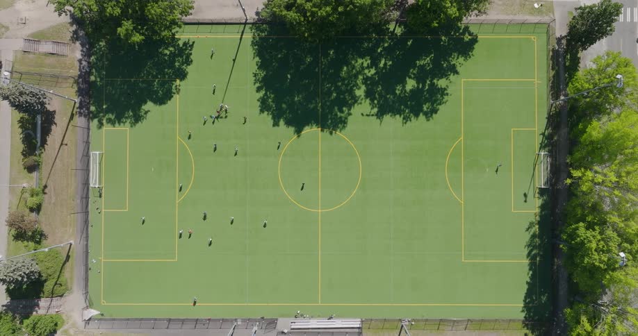 Top down view of people playing soccer on a turf field on a sunny day