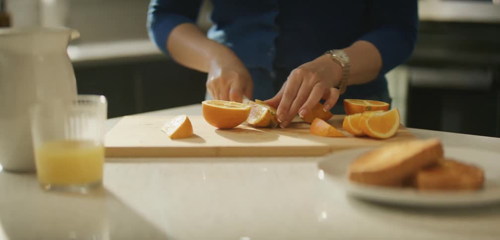A woman is cutting oranges in the kitchen