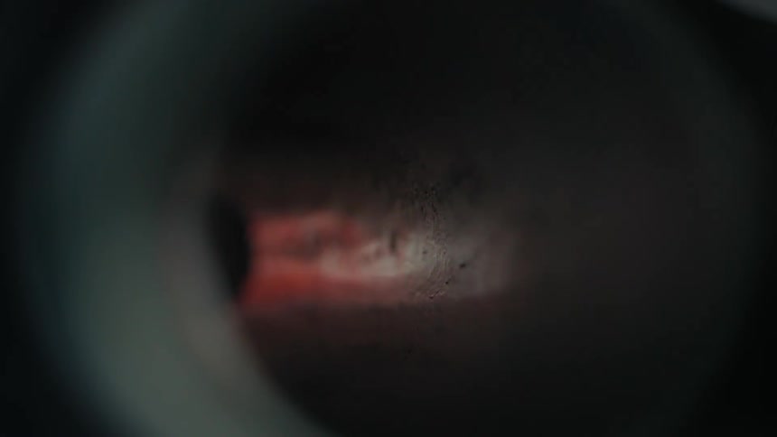 A metal pipe has a small burst of fire and flames that briefly flashes through it
