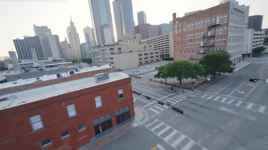 Aerial view of an urban Dallas intersection with cars and pedestrians and buildings of different heights in a metropolis