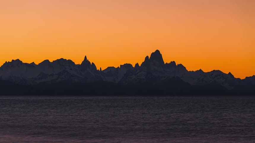 A body of water is near a mountain range at sunset