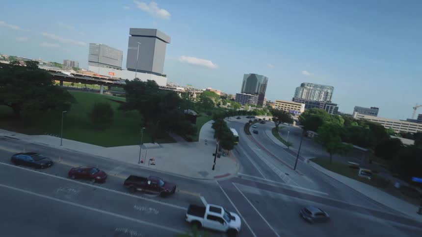 Aerial panorama of overpasses, intersections, tall buildings, and green spaces in downtown Dallas