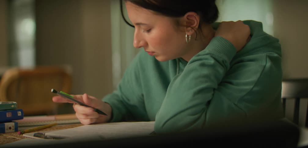 A young woman is sitting at a table and working on a homework project