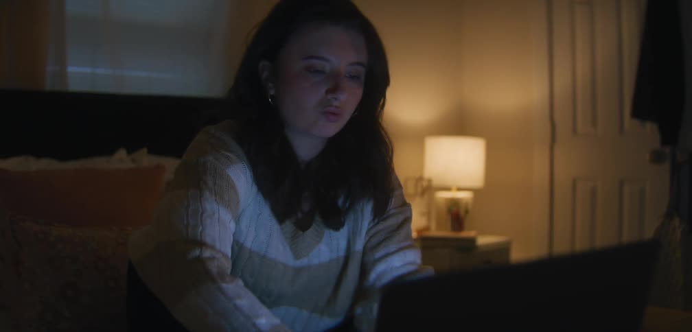 A young female uses her laptop in bed