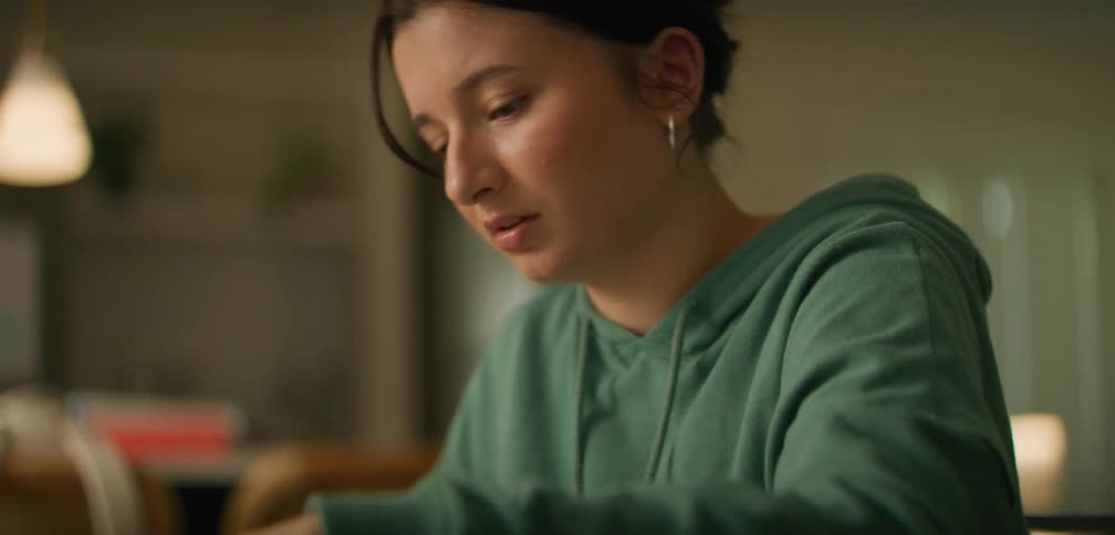A girl is sitting at a table and thinking while finishing homework