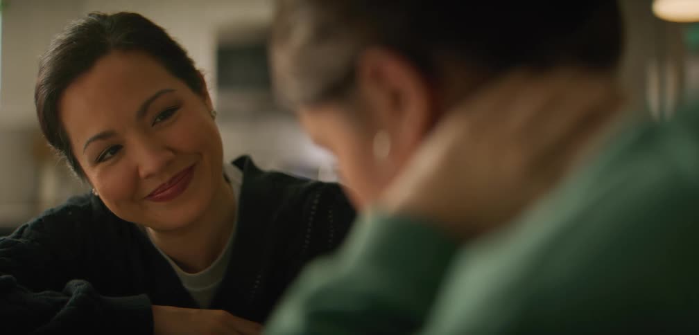 Mother is smiling at her daughter as they sit at a table