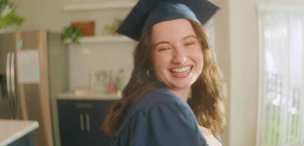 A happy young woman in a graduation cap looking at the camera