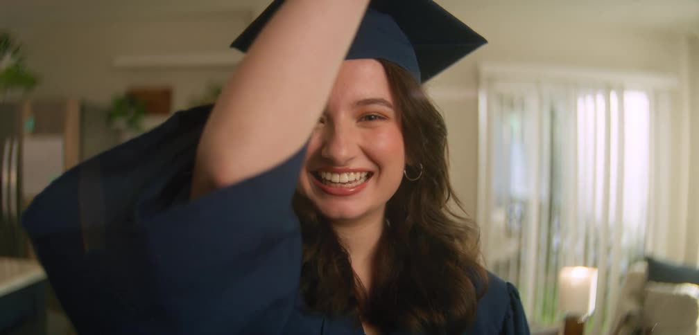 A woman smiles in her cap and gown