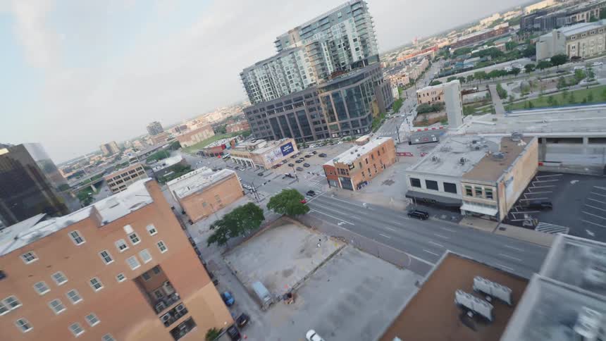 Aerial scene of a city with large buildings and intersections with vehicle traffic