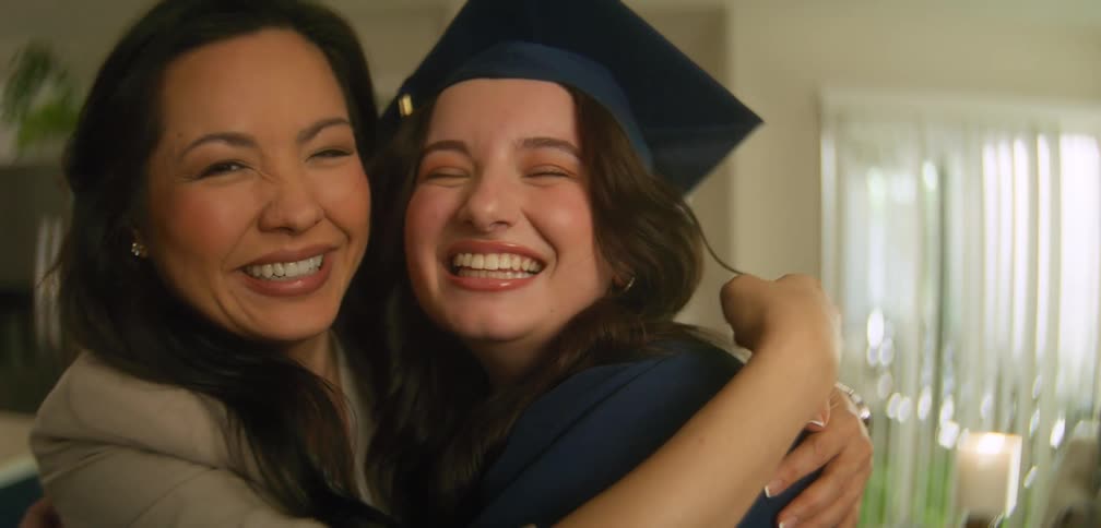 A mother and daughter are posing for the camera on graduation day