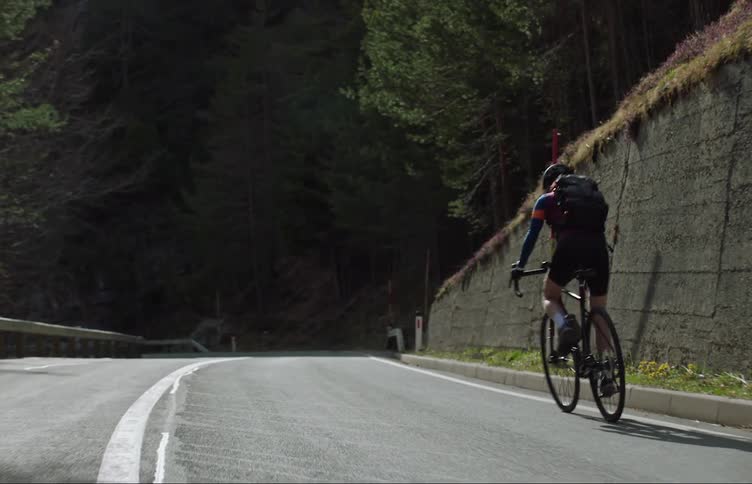 Person is biking on a street while wearing a backpack and helmet