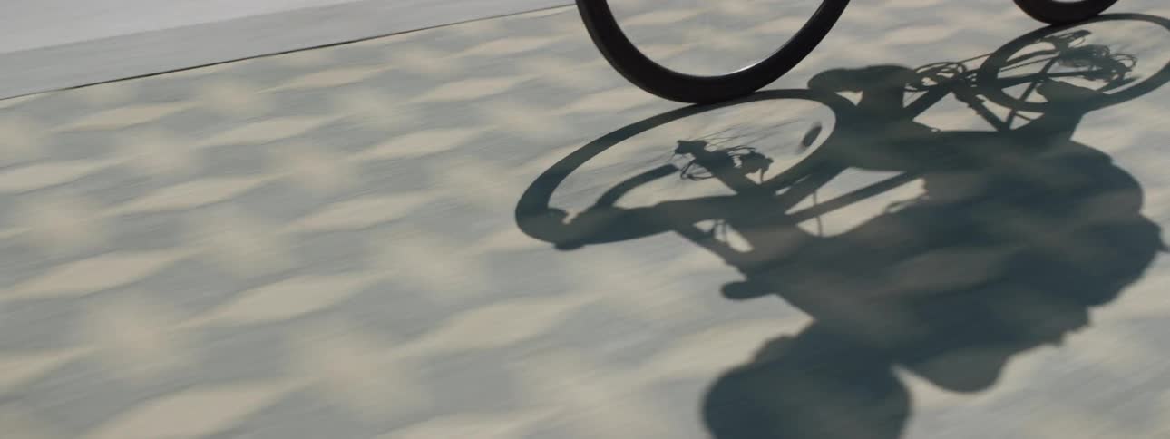 The shadow of a person riding their bicycle outdoors