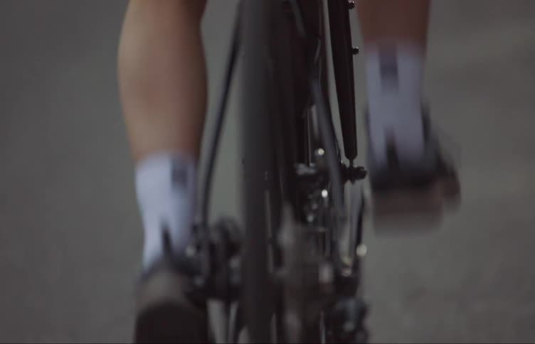 A person is riding their bicycle on tarmac and pedaling fast