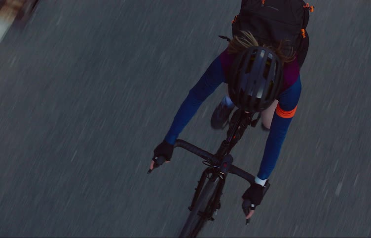 A female bicyclist pedals quickly as she travels along a road