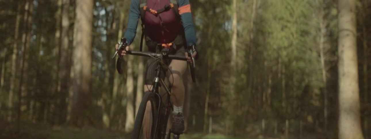 A person rides a bicycle on a hiking trail through the forest