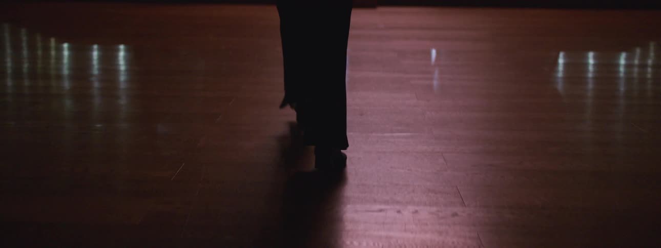A person is walking on hardwood floors towards a stage