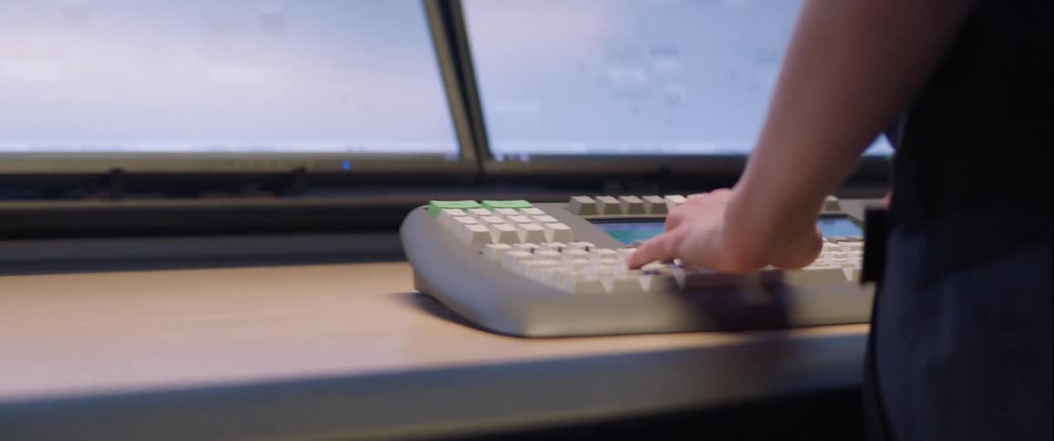 A person is standing in a room and typing on a keyboard