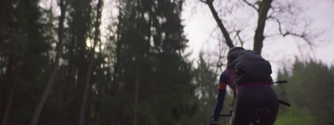 A cyclist is driving on a trail in a wooded park