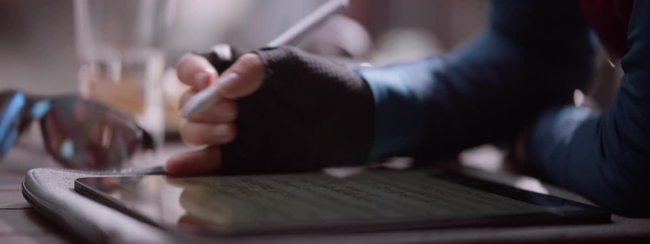 Woman wearing finger less gloves writes on a tablet using a stylus