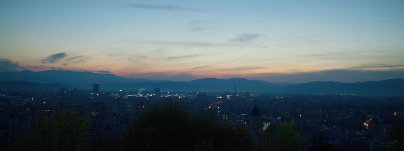 Dusk in the city with buildings illuminated under a sky that transitions from blue to orange