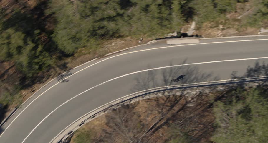 Overhead view moutain biking down a winding road through the mountains