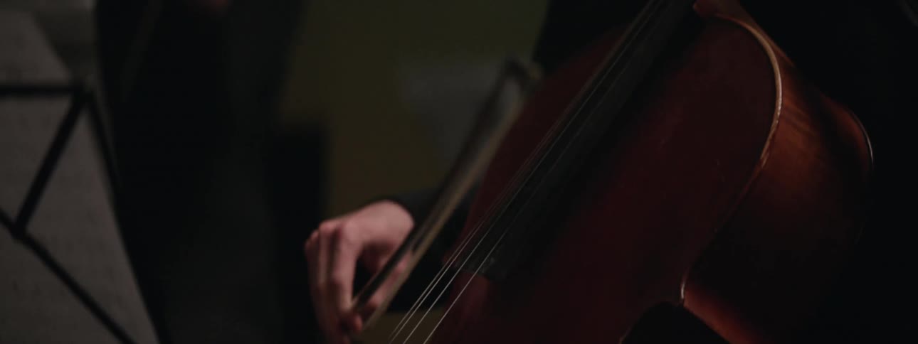 A person is sitting down and playing a string instrument