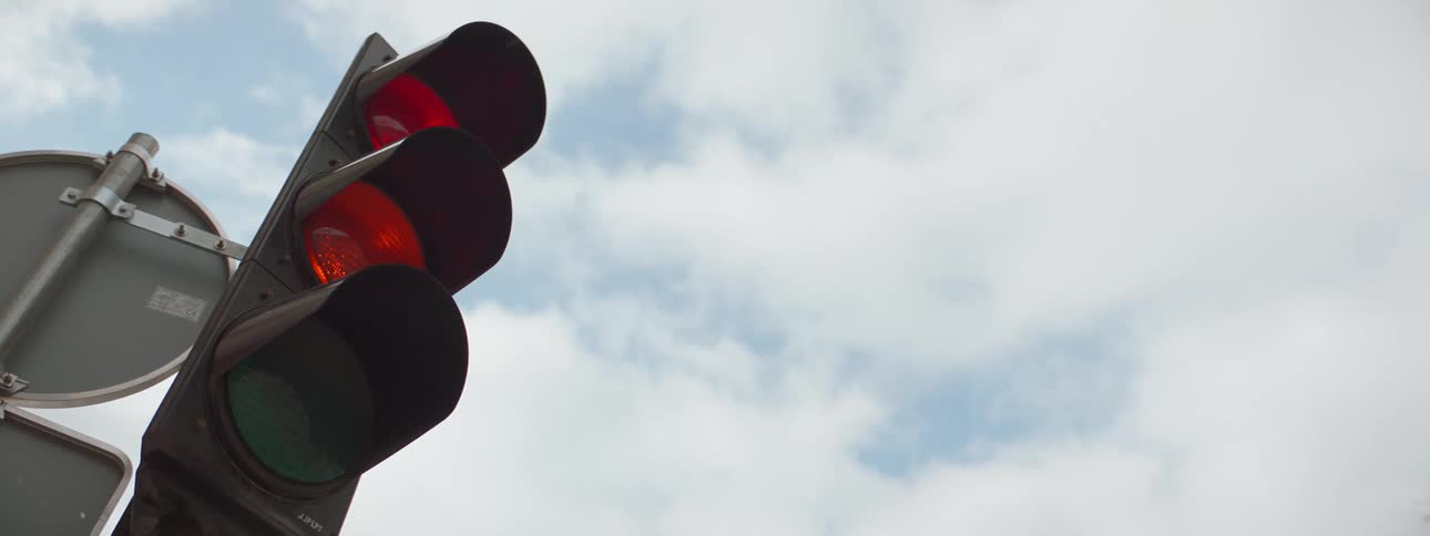 A closeup view of a traffic light against a cloudy sky