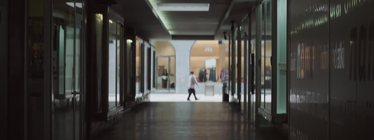 People walking past a corridor in the mall with an employee cleaning their shop behind them