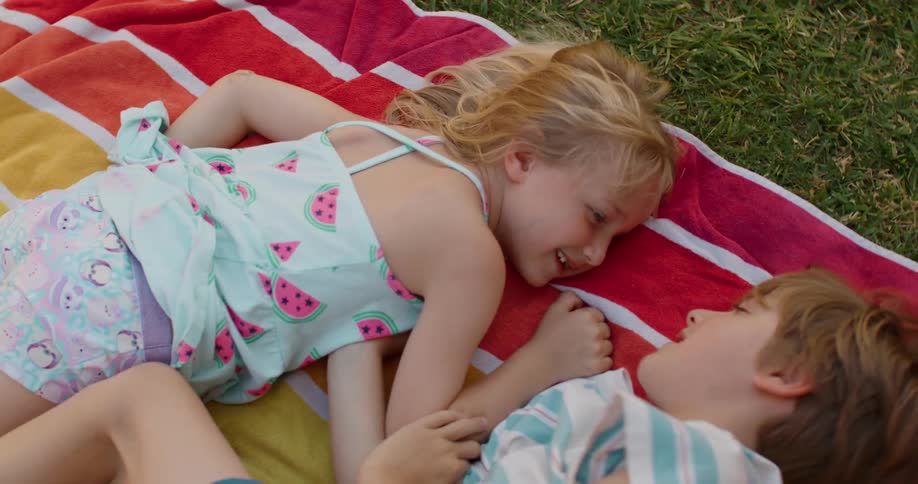 A pair of young children tickle each other and laugh while playing outdoors