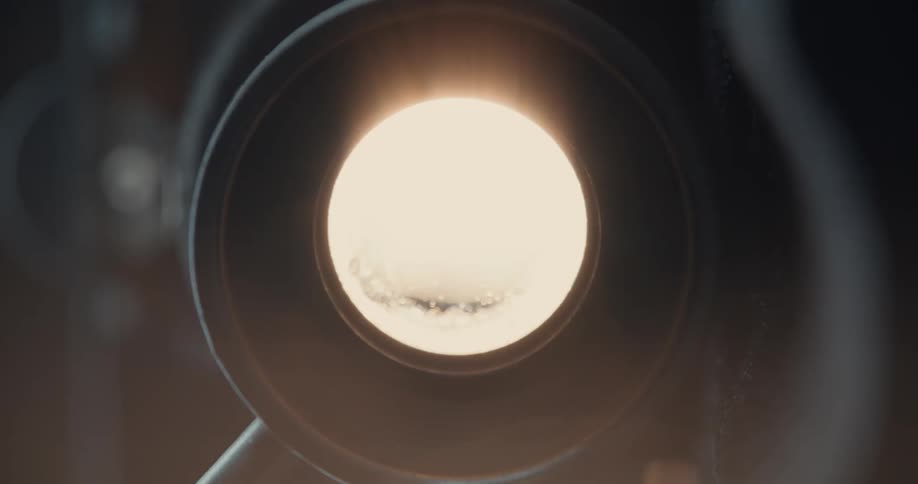 Video camera lens opens to show reflection of coastal landscape